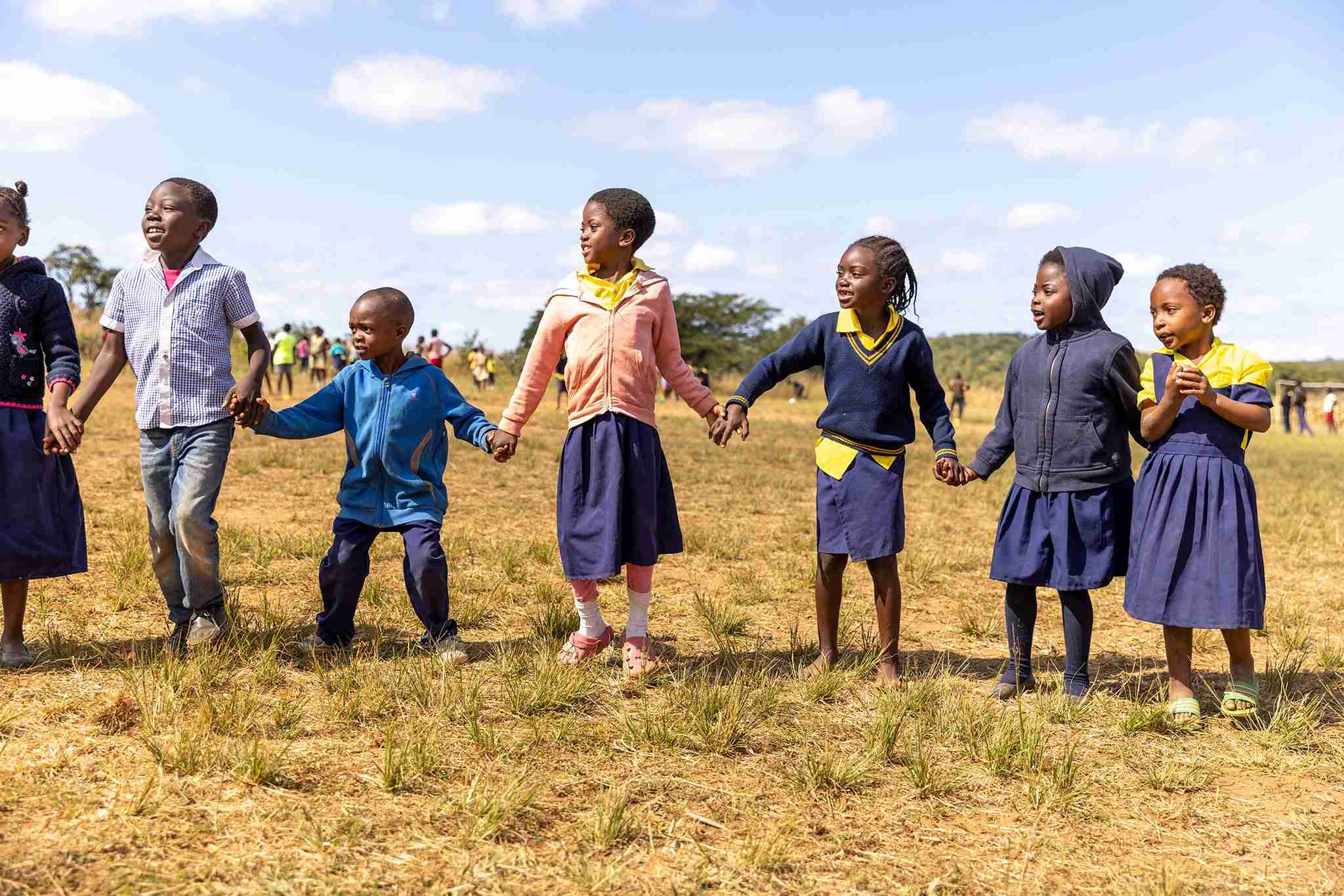 A group of children holding hands in a circle.