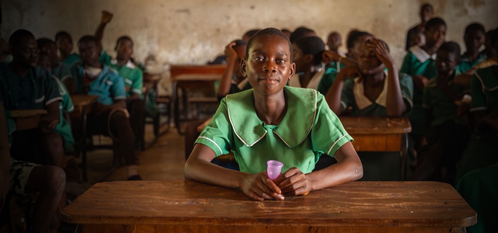 A girl smiling at her school desk.