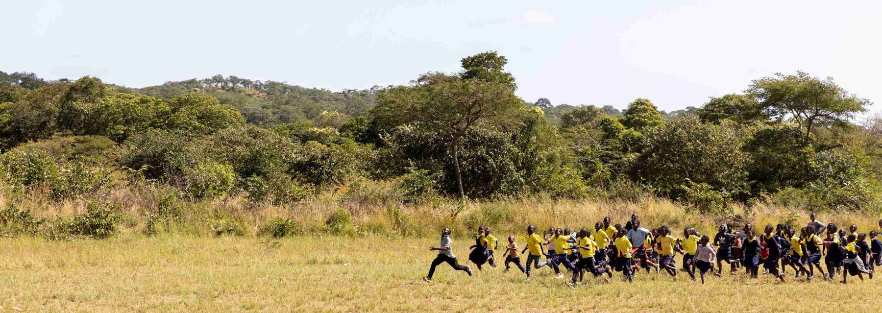 A teacher leading a group of children in a game on a school field.
