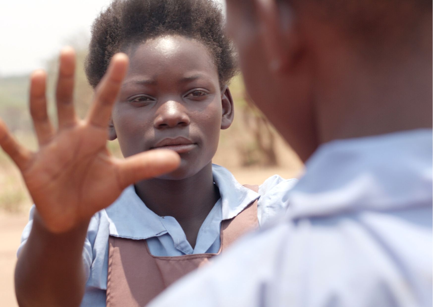 A girl holding up her hand towards another child during a game on the school field.