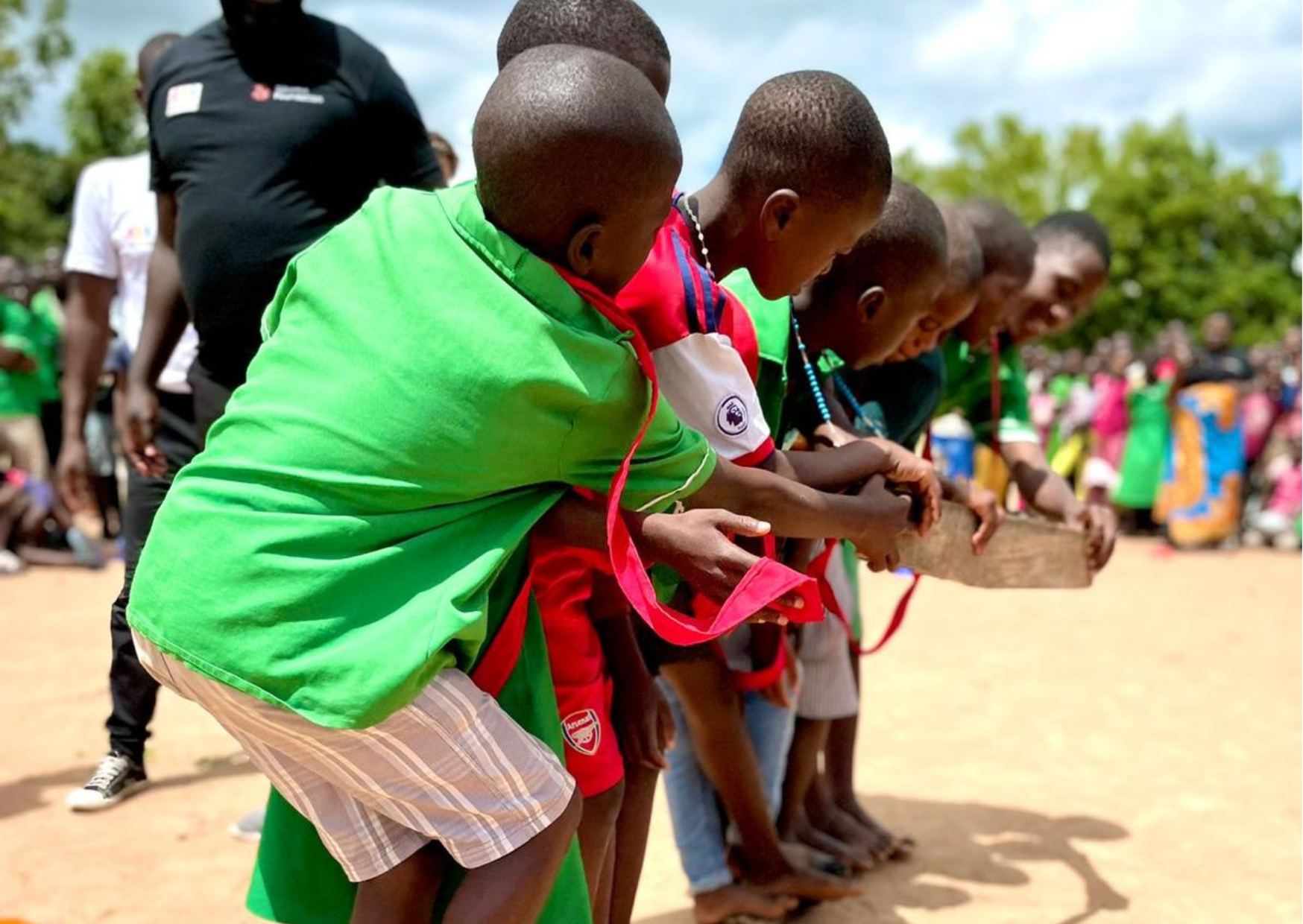 Children in a row passing materials to each other during a team game outdoors.