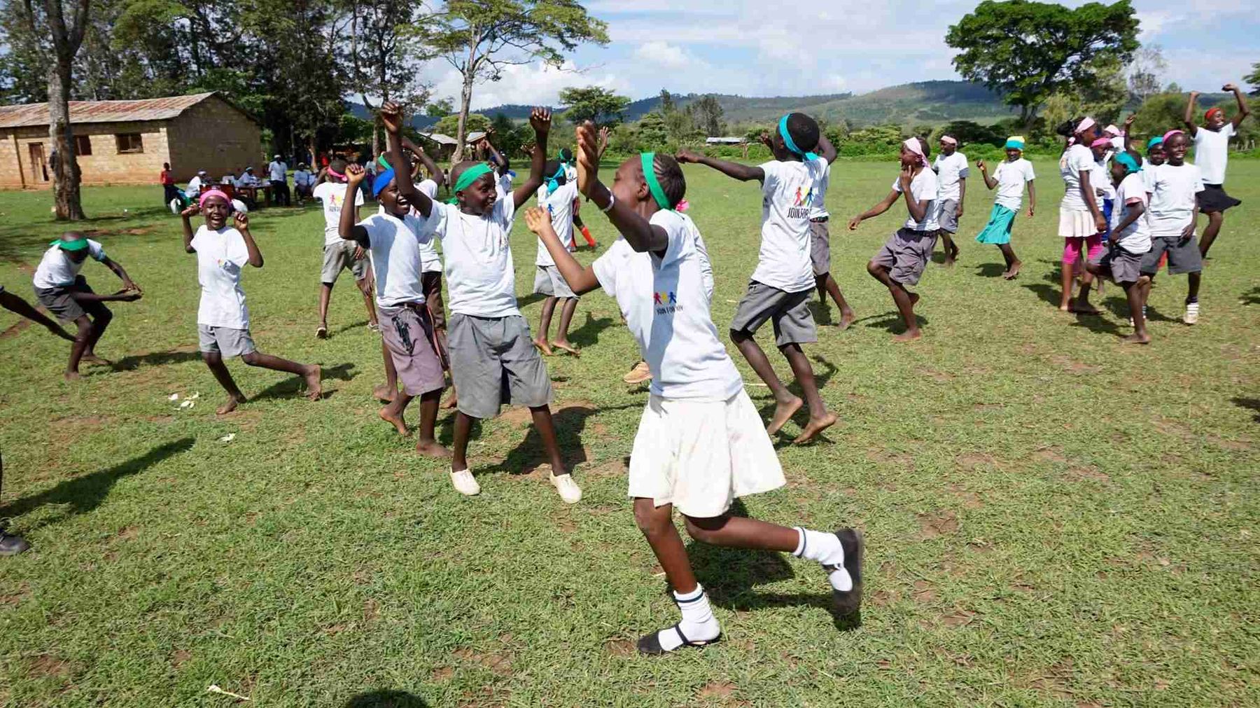 Children and a coach laughing together during a game.