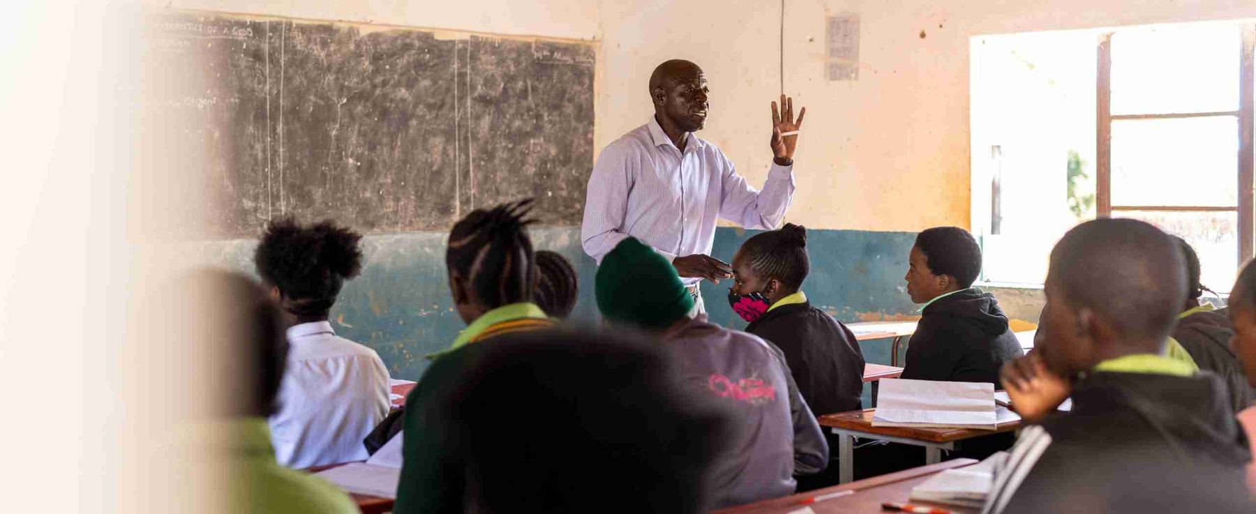 A classroom of children with their hands in the air.