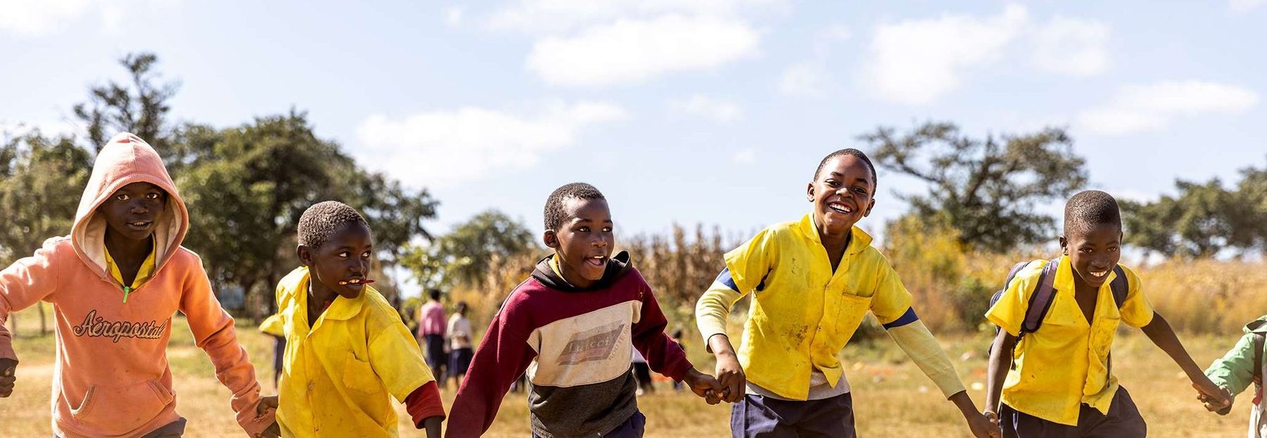 Children running across a schoolyard, laughing.