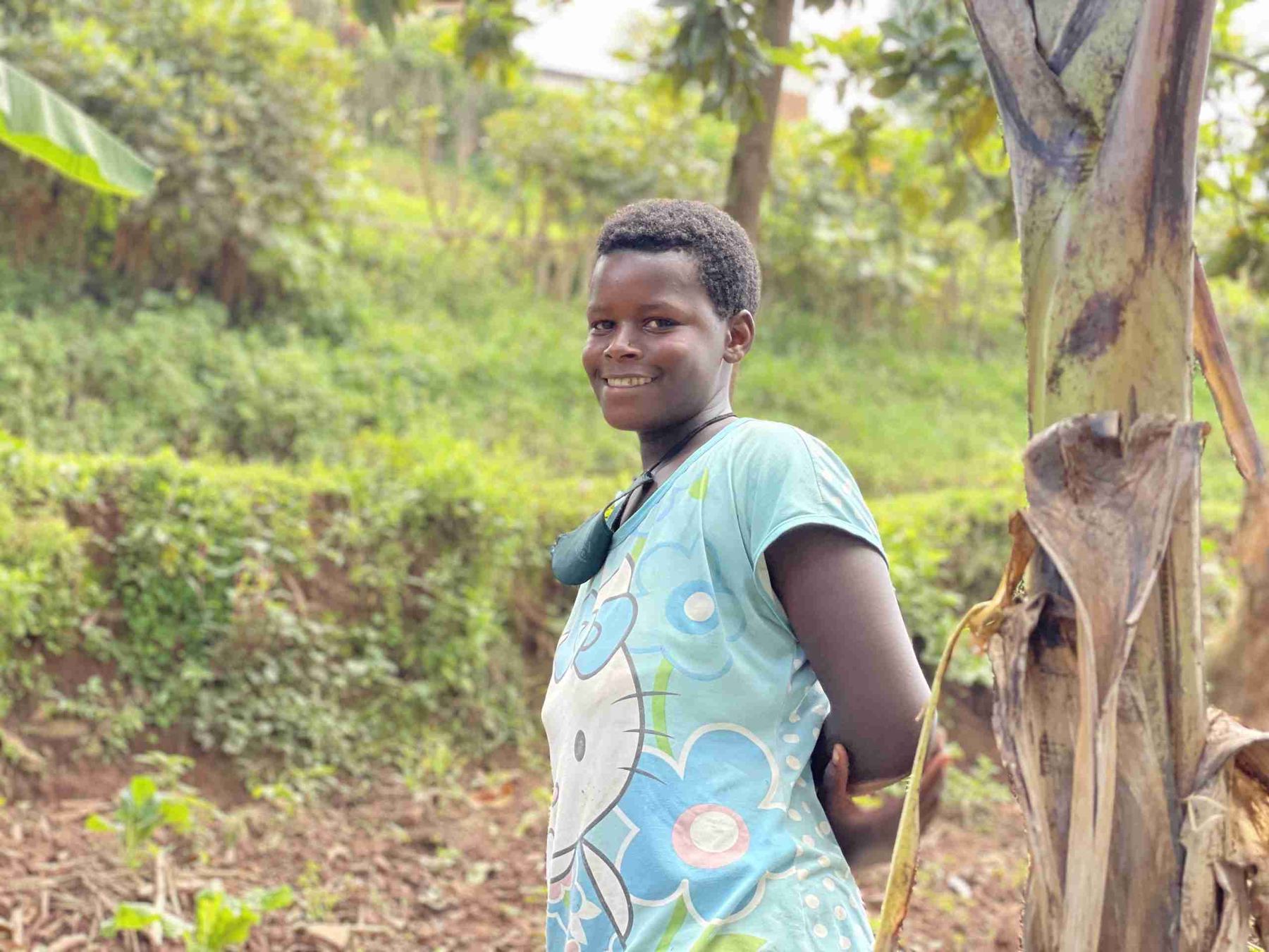 A girl sitting against a tree with a notebook on her lap.
