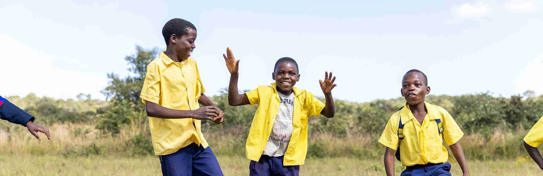 Children waving at the camera during a Join for Joy sports day.