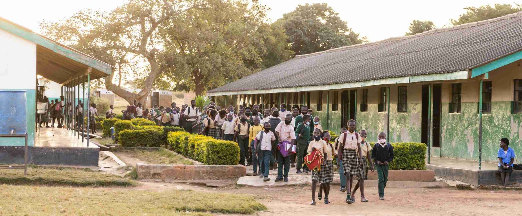 A film crew recording a lesson on a school field in East Africa.