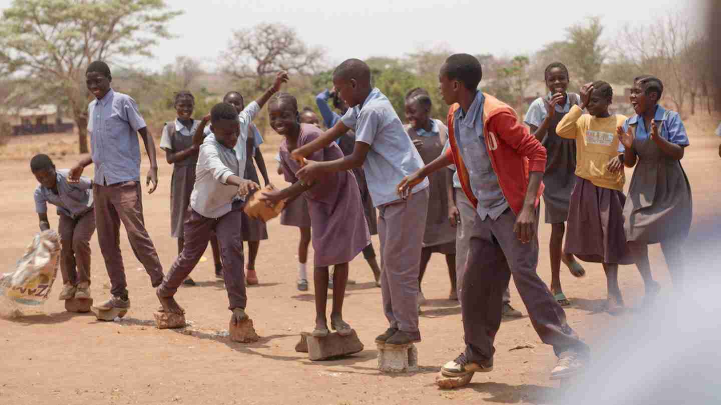 Children laughing during a playful lesson outdoors.